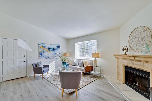 living room with lofted ceiling, a tile fireplace, and light hardwood / wood-style flooring