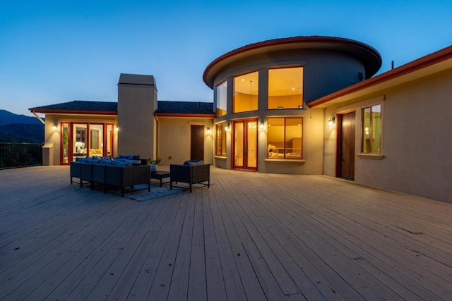 deck at dusk featuring a mountain view and an outdoor living space