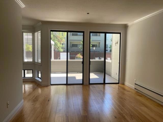 doorway with baseboard heating, hardwood / wood-style flooring, and ornamental molding