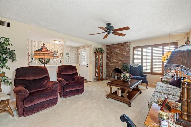 living room featuring ceiling fan, light colored carpet, a brick fireplace, and a textured ceiling