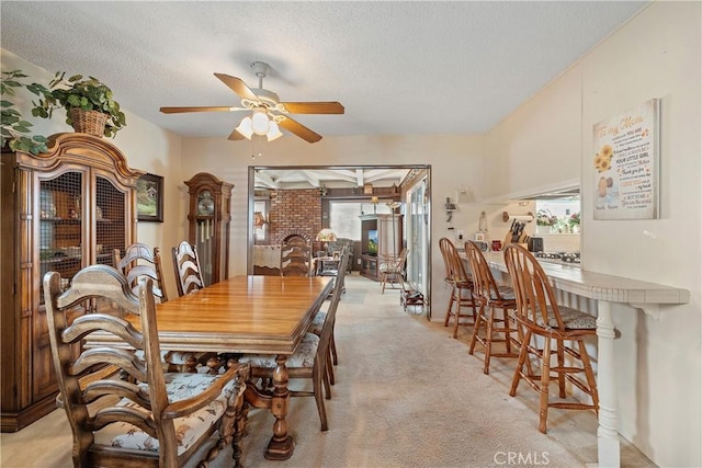 carpeted dining room with a textured ceiling, ceiling fan, and a healthy amount of sunlight