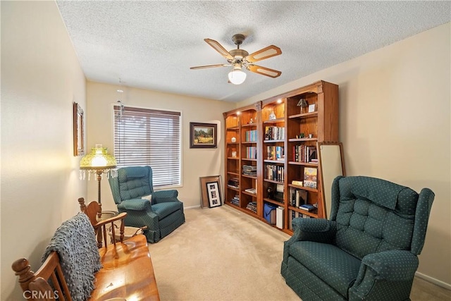 living area featuring a textured ceiling, ceiling fan, and light carpet