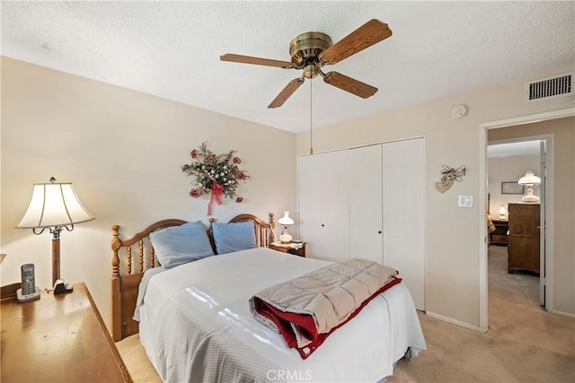 carpeted bedroom featuring a textured ceiling, ceiling fan, and a closet