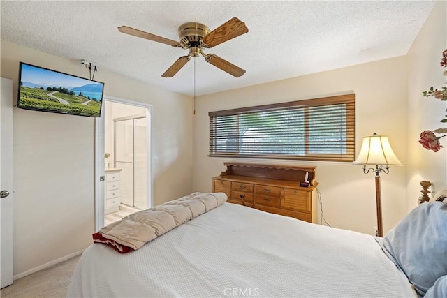 bedroom featuring ceiling fan, light carpet, ensuite bath, and a textured ceiling