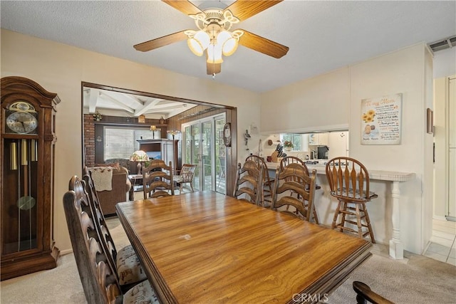 dining room with a healthy amount of sunlight, a textured ceiling, ceiling fan, and light carpet