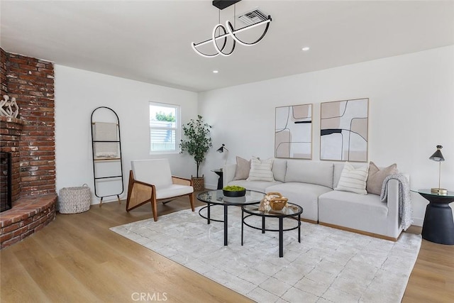 living room featuring a brick fireplace, an inviting chandelier, and light hardwood / wood-style floors