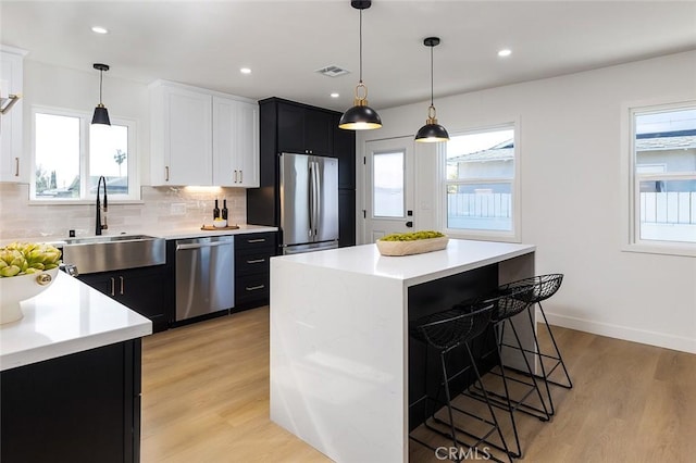 kitchen featuring a kitchen island, appliances with stainless steel finishes, light hardwood / wood-style floors, and decorative backsplash