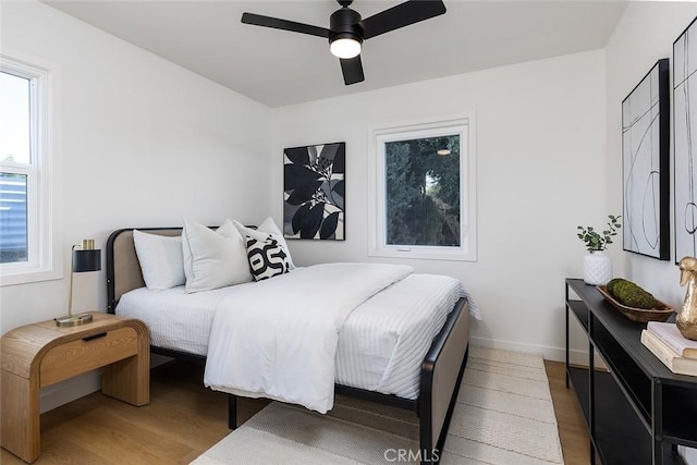 bedroom with hardwood / wood-style floors, ceiling fan, and multiple windows