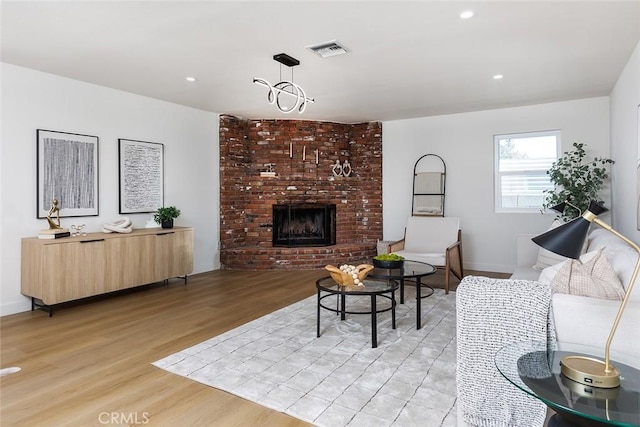 living room with a fireplace, light hardwood / wood-style floors, and a chandelier