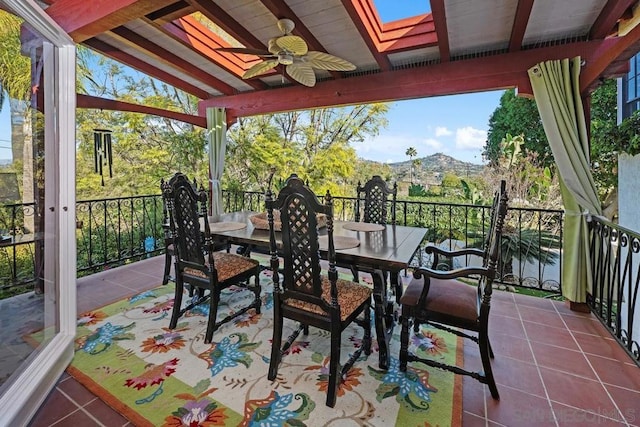 sunroom with lofted ceiling with skylight, ceiling fan, and a mountain view