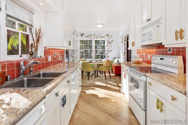 kitchen featuring white appliances, white cabinetry, decorative backsplash, sink, and light hardwood / wood-style flooring