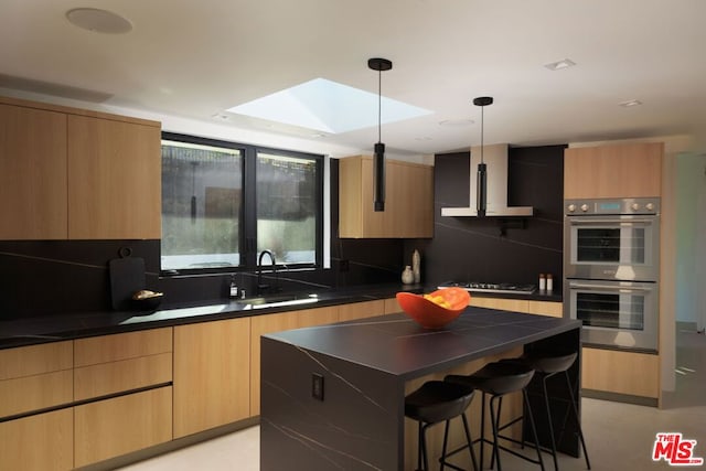 kitchen featuring a kitchen bar, a skylight, a kitchen island, pendant lighting, and appliances with stainless steel finishes