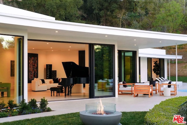 rear view of house featuring an outdoor living space with a fire pit and a patio