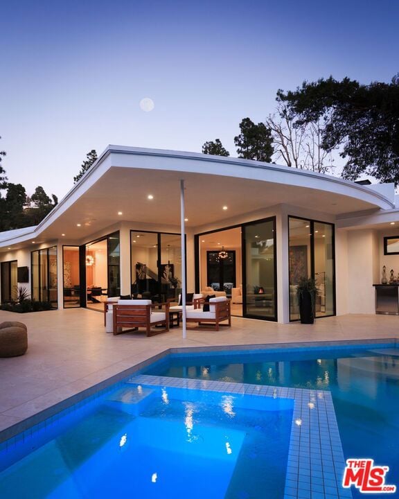 pool at dusk with an outdoor hangout area and a patio