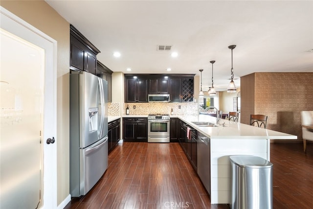 kitchen featuring pendant lighting, sink, a breakfast bar area, kitchen peninsula, and stainless steel appliances