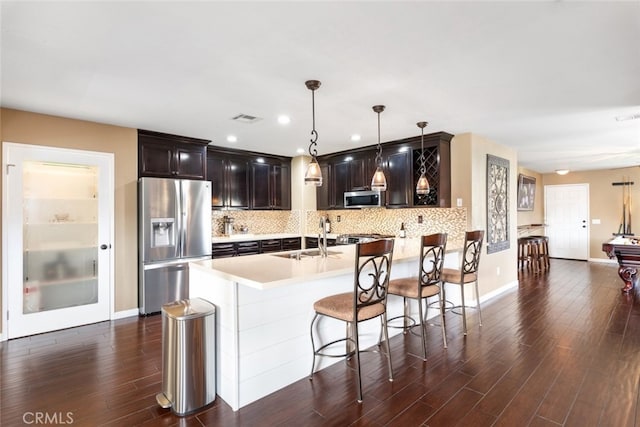 kitchen with pendant lighting, appliances with stainless steel finishes, sink, and backsplash