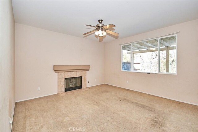 unfurnished living room featuring a tile fireplace, light carpet, and ceiling fan