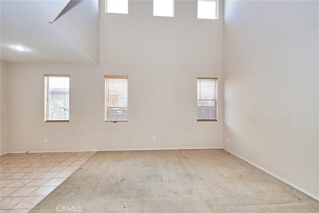 empty room featuring a towering ceiling and light tile patterned floors