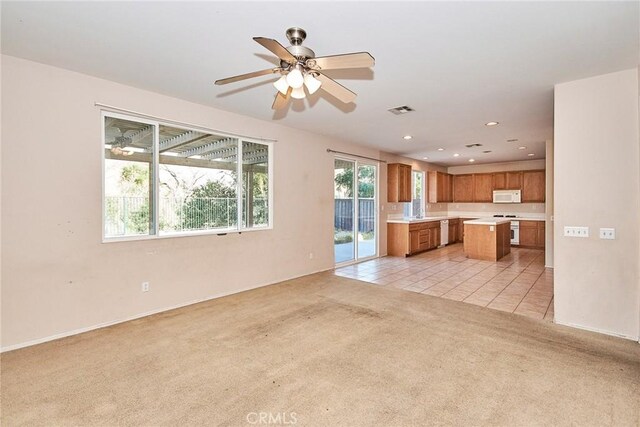 unfurnished living room with light carpet and ceiling fan