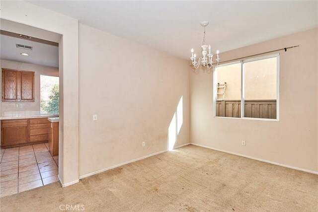 carpeted empty room with a notable chandelier