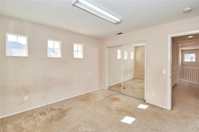 unfurnished bedroom with light colored carpet and a closet