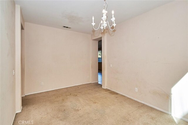 unfurnished room featuring carpet flooring and a chandelier