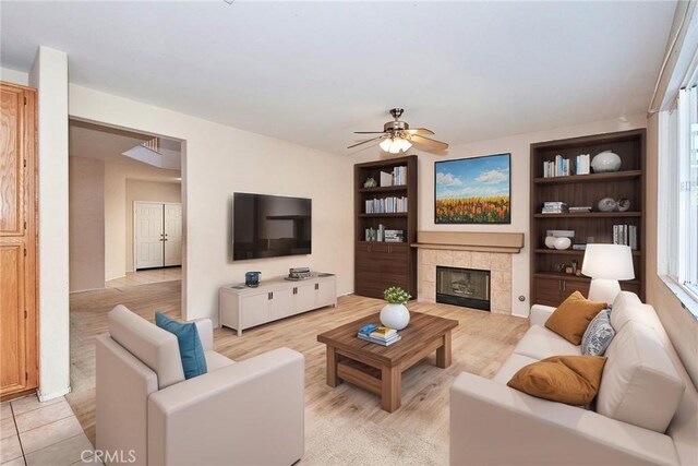 living room with a tiled fireplace and ceiling fan