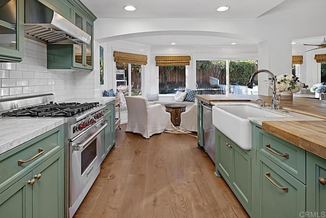 kitchen featuring stainless steel appliances, sink, green cabinets, tasteful backsplash, and ventilation hood