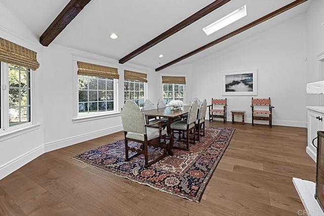 dining space featuring vaulted ceiling with skylight, a wealth of natural light, and hardwood / wood-style floors