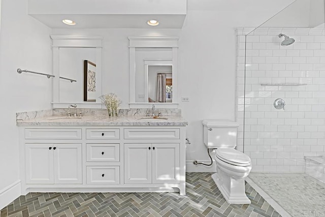 bathroom with a tile shower, vanity, and toilet