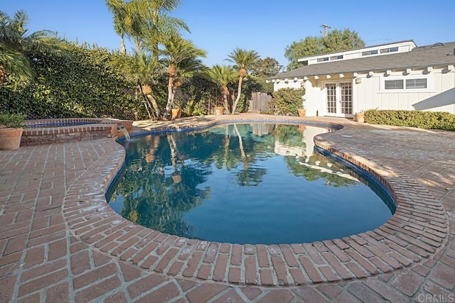 view of pool featuring french doors, an in ground hot tub, an outdoor structure, and a patio area