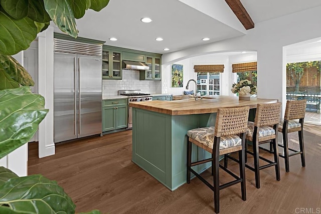 kitchen with sink, green cabinets, beamed ceiling, high end appliances, and butcher block countertops