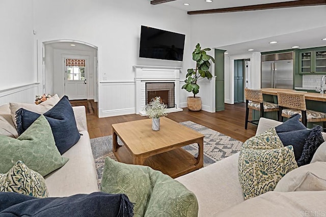 living room featuring dark hardwood / wood-style flooring, a brick fireplace, and lofted ceiling with beams