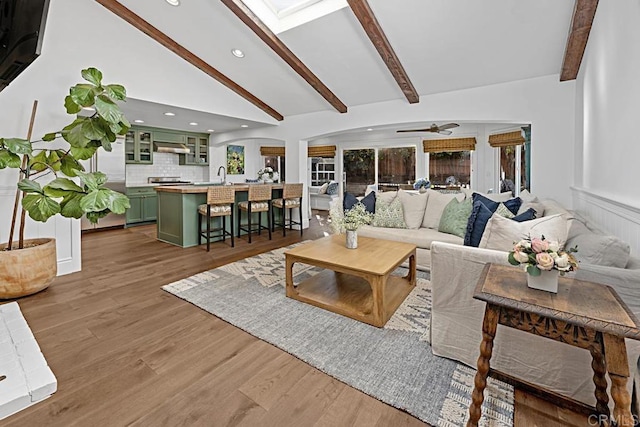 living room featuring ceiling fan, lofted ceiling with beams, sink, and wood-type flooring