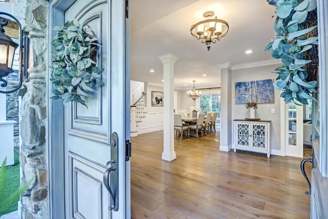 entrance foyer featuring hardwood / wood-style flooring, ornate columns, crown molding, and a chandelier