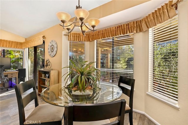 dining area featuring hardwood / wood-style flooring, an inviting chandelier, and vaulted ceiling