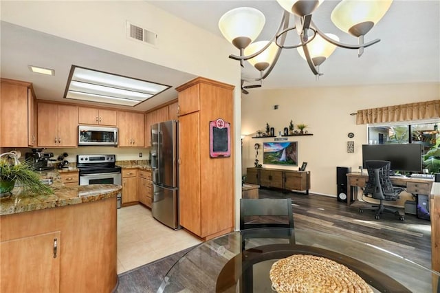 kitchen featuring stainless steel appliances, vaulted ceiling, light tile patterned floors, stone countertops, and a notable chandelier