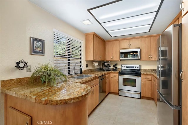 kitchen with stainless steel appliances, sink, light stone countertops, and kitchen peninsula