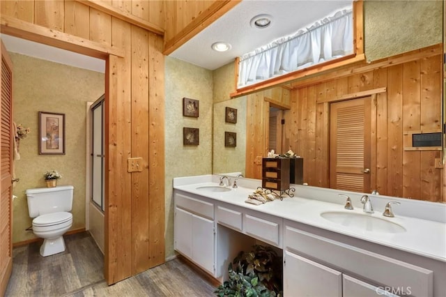 bathroom with hardwood / wood-style floors, wood walls, vanity, and toilet