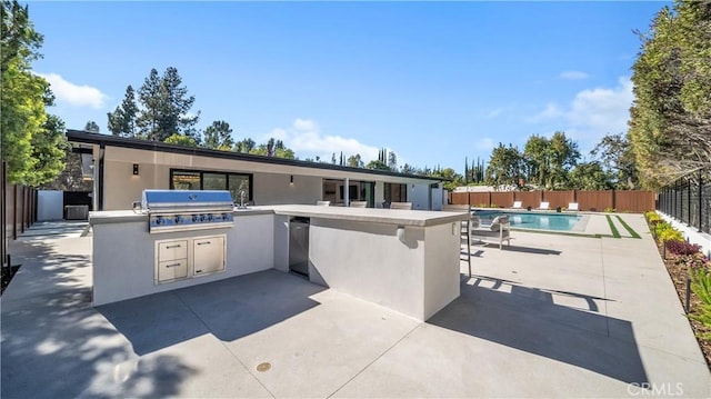 exterior space with grilling area, an outdoor kitchen, and a fenced in pool