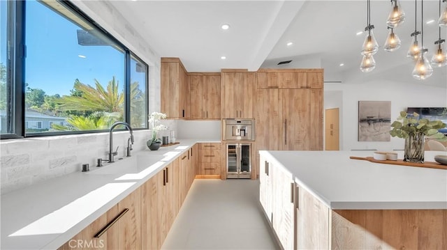 kitchen featuring oven, sink, hanging light fixtures, light brown cabinets, and beverage cooler