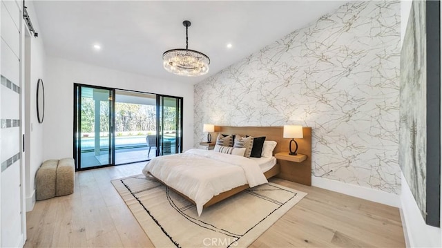 bedroom featuring light wood-type flooring, access to outside, and a notable chandelier