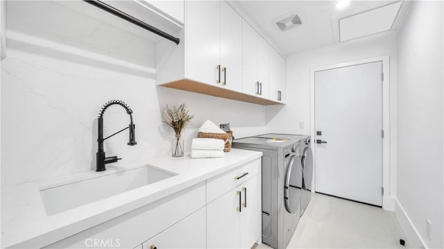 laundry room with cabinets, washing machine and clothes dryer, and sink