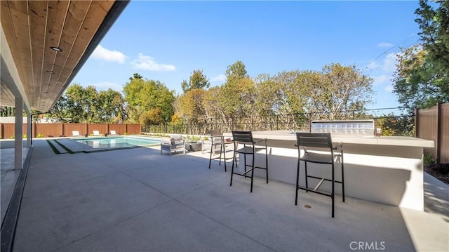 view of patio with exterior bar and a fenced in pool