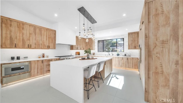 kitchen with pendant lighting, a kitchen island, light tile patterned flooring, stainless steel gas cooktop, and a kitchen breakfast bar