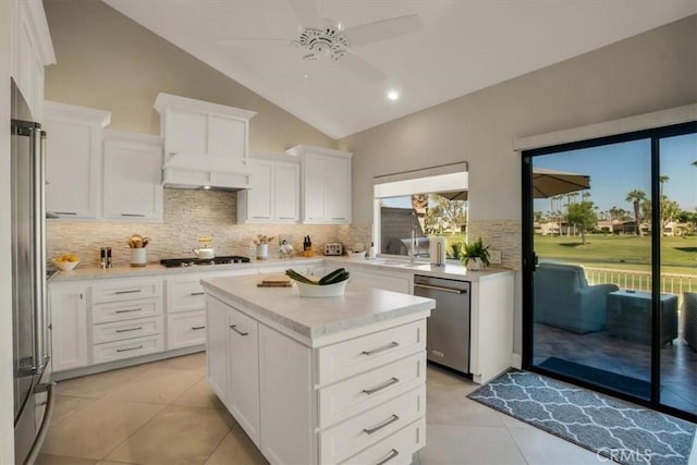 kitchen with stainless steel appliances, white cabinetry, lofted ceiling, and a center island