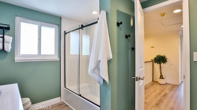 bathroom with toilet, combined bath / shower with glass door, and hardwood / wood-style floors