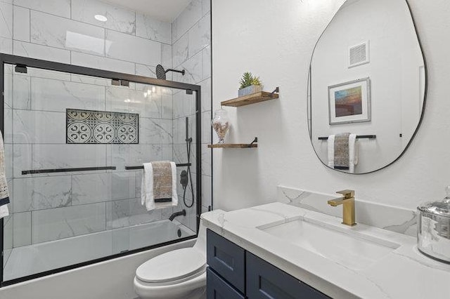 full bathroom featuring toilet, combined bath / shower with glass door, and vanity