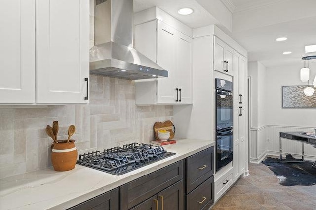 kitchen featuring white cabinetry, black appliances, light stone counters, and wall chimney range hood