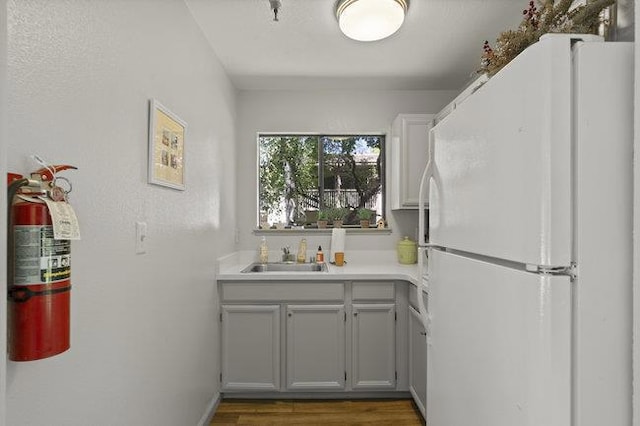 kitchen featuring white fridge, gray cabinets, dark hardwood / wood-style flooring, and sink